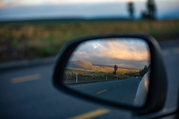 landscape seen through the rearview mirror of the car