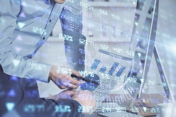 Double exposure of chart with businessman typing on computer in office on background. Concept of hard work.