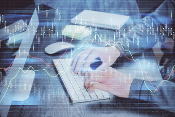 Stock graph with businessman typing on computer in office on background. Concept of analysis. Double exposure.