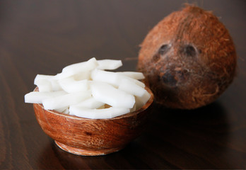 brown coconut fruit and slices of natural white coconut in a wooden plate