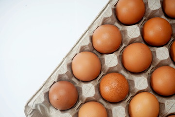 Raw brown chicken eggs in a paper grey crate carton isolated on white background.