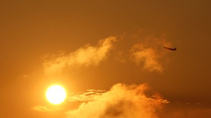 夕日と飛び去って行く飛行機