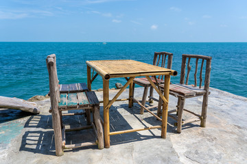 Bamboo table and wooden chairs in empty cafe next to sea water in tropical beach . Island Koh Phangan, Thailand