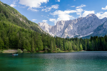 People boating and enjoy beautiful land scape of Lago di Fusine, the lake with background of Julian alps in Italy.