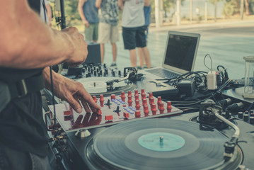 Outdoor music party. Dj playing on vinyl. Dj's hands and turntable close up, blurred people on the background