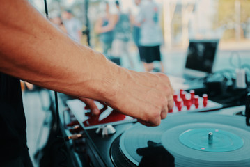 Outdoor music party. Dj playing on vinyl. Dj's hands and turntable close up, blurred people on the background