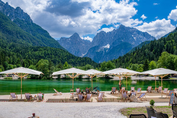 Tourist sit on the chairs with umbrella looking at beautiful landscape of Jasna lake, the small turquoise lake with background of mountain.