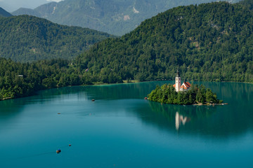 Fototapeta premium Beautiful landscape of Lake Bled with Pilgrimage Church of the Assumption of Maria with tourist kayaking in the lake.