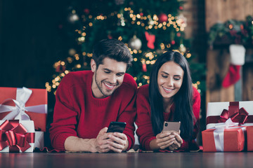 Close up photo of two romantic people use cell phone lying on floor with git boxes enjoy christmas x-mas holidays vacation in house indoors