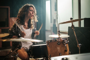 Fototapeta na wymiar Woman playing drums during music band rehearsal