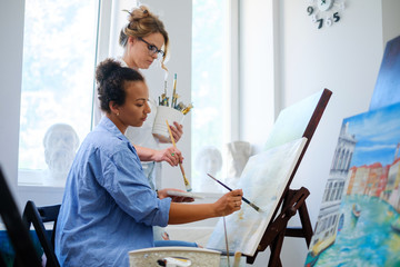 Obraz premium Creative painter and her protege working in a studio