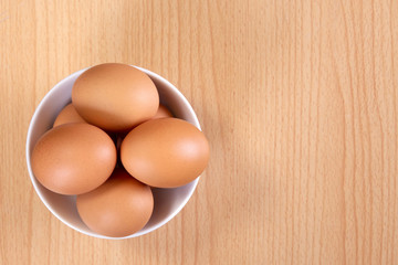 top view of eggs in bowl on wooden background