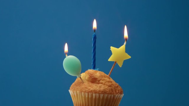 muffin with some candle decoration on a blue background
