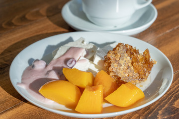 Curd cheese poured fruit yogurt, peaches, honeycombs and cup coffee on wooden table. Breakfast concept. Closeup