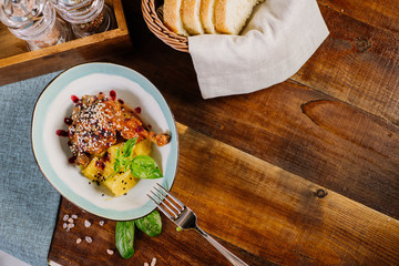 Baked chicken leg with sauce and fruits on the wooden background