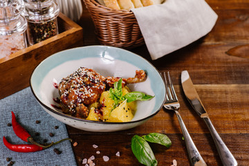 Baked chicken leg with sauce and fruits on the wooden background