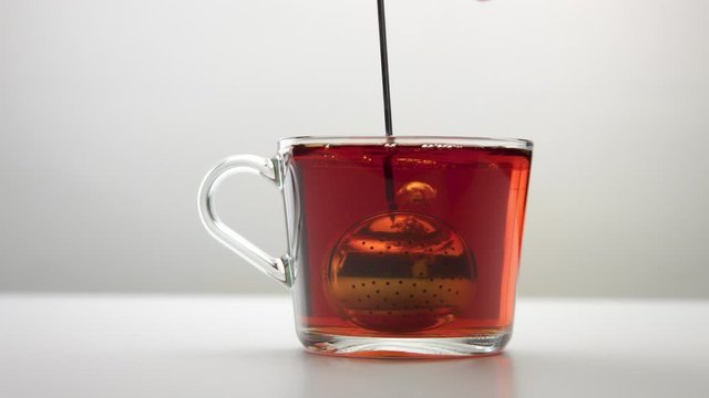 slow motion of an intensive movement of the infuser spoon with tea in cup