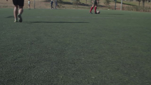 Close-up of soccer player legs dribbling during game. Skillful football dribbler attempting to propel soccer ball toward opponents' goal through individual control of ball, tricks and feints in pitch.