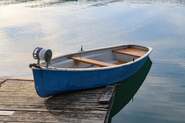 Blue fishing boat stands on a quiet lake