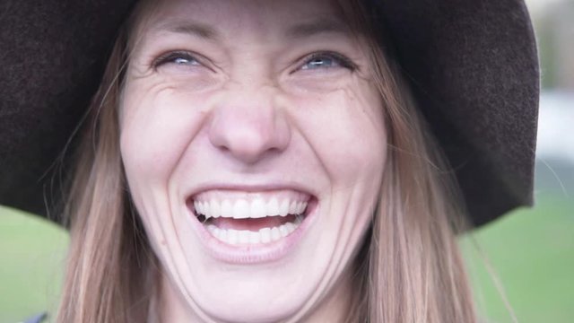 Woman in a hat laughs merrily, close-up, time lapse