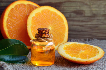 Orange essential oil in a glass bottle and fresh fruits on old wooden table.Citrus oil for skin care, spa, wellness, massage, aromatherapy and natural medicine.Selective focus.