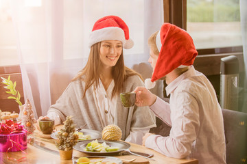 guy and girl couple celebrate Christmas in cafe dressed in Christmas   hats