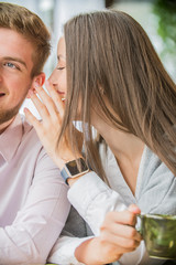 the girl speaks into the ear of the guy a secret