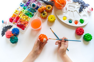 child paints a decorative pumpkin with paint. Halloween holiday.