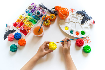 child paints a decorative pumpkin with paint. Halloween holiday.