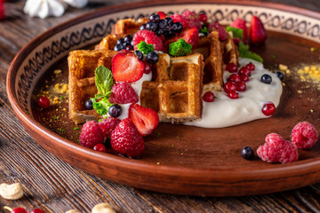 Belgian waffles with berries, nuts and cream cheese in a plate on a wooden table, Tasty breakfast, Horizontal orientation
