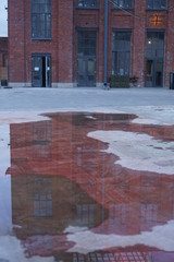 reflection of a brick building in a puddle