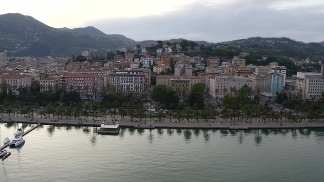 Aerial flying up to Italian city and tilting down to busy road. Shot in La Spezia, Italy