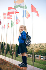 Little students go to school. Schoolchildren on background of flags of foreign countries.