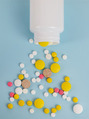 Several tablets fall out of the plastic jar on the surface. Background image on medical and pharmaceutical topics