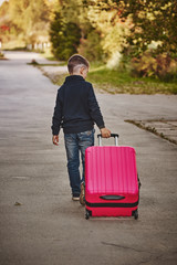 A boy with a suitcase is on the road on a journey, preparing for the trip