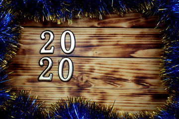 on a wooden surface lies tinsel with numbers 2020