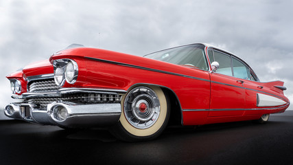 Zijaanzicht van een klassieke Amerikaanse auto uit de jaren vijftig. Lage hoekmening met rode verf en chromen spatbord en grill.