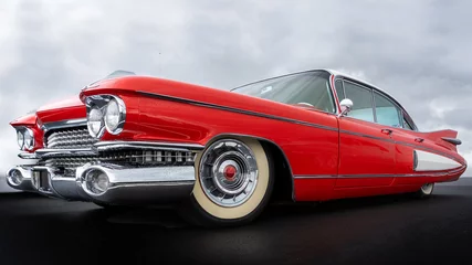  Zijaanzicht van een klassieke Amerikaanse auto uit de jaren vijftig. Lage hoekmening met rode verf en chromen spatbord en grill. © mikevanschoonderwalt