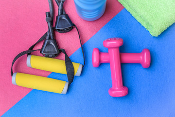 Still life view of fitness object over a colorful background. Weights, elastic rope and water bottle ready for a healthy daily workout. Close up of equipment. Health sport work out keeping fit concept