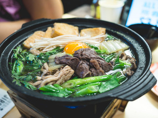 Bowl of hot Japanese soup with beef, egg, mushroom, vegetable in the restaurant