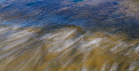 Waves on the seashore captured with a slow shutter speed. Natural abstract motion background.