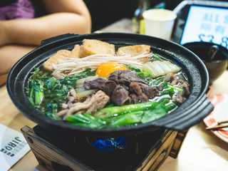 Bowl of hot Japanese soup with beef, egg, mushroom, vegetable in the restaurant