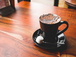 Cup of hot chocolate with dark brown chocolate foam on top with sugar