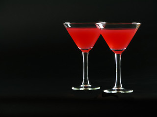 Classic Bacardi alcoholic cocktail of bright red color from white rum, lime juice and grenadine, in two conical cocktail glass on a dark background