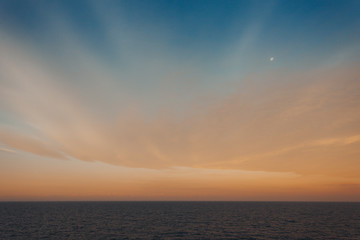 Moon over the sea and colorful sky and clouds after sunset