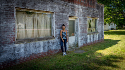Obraz na płótnie Canvas woman standing in front of dilapidated and abondoned restaurant in Virginia