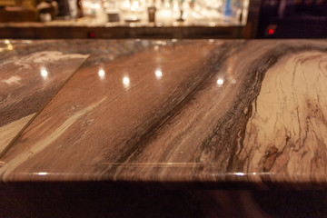 Bar counter made of gold-colored marble with lights reflections