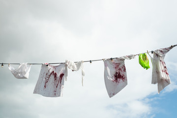 Bloody clothes hanging on a rope on sky background - obrazy, fototapety, plakaty