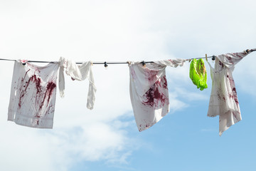 Bloody clothes hanging on a rope on sky background