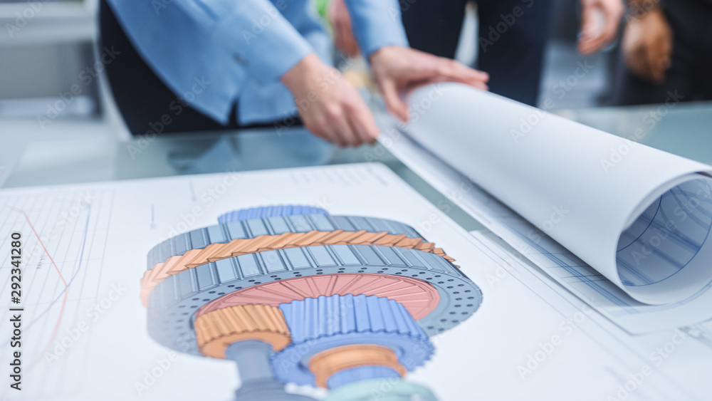 Poster In the Industrial Engineering Facility: Diverse Group of Engineers and Technicians on a Meeting Gather Around Table Unravel Sheets of Engine Design Technical Drafts, Have Discussion, Analyse Drawings